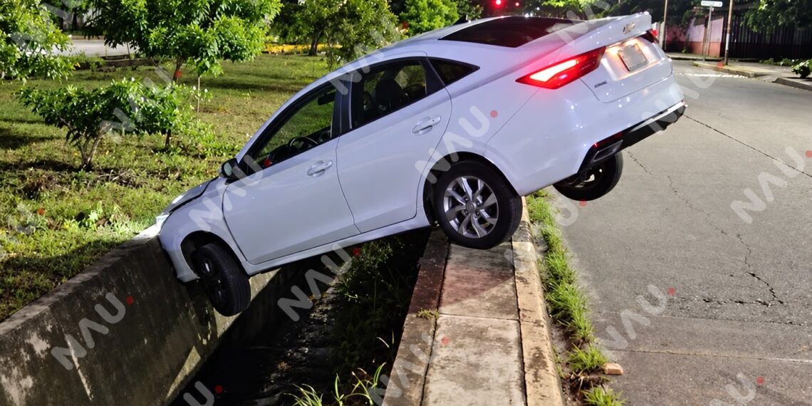 Automóvil queda abandonado tras caer a dren pluvial en el par vial